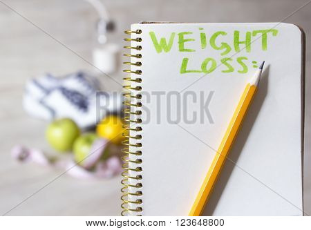 paper notebook with weight loss plan for way to perfect body and fruits, sport  sneakers in the background
** Note: Soft Focus at 100%, best at smaller sizes