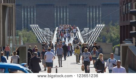 LONDON, UK - SEPTEMBER 10, 2015: Lots of people walking via Millennium bridge on the Thames embankment. Tate Modern gallery on the background