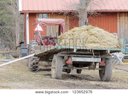 STOCKHOLM SWEDEN - MAR 20 2016: Old red tractor and a tractor trailer filled with hay at Oeverjarva Gard Mars 20 2016 Stockholm Sweden
