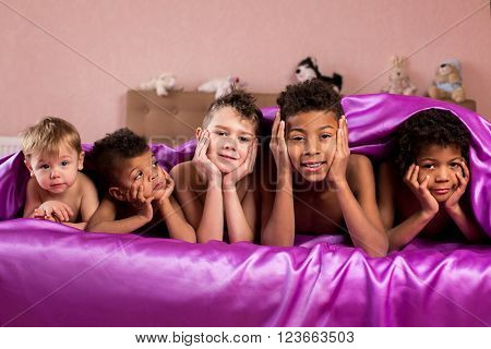 Five young boys under blanket. Smiling tired kids on bed. Wish we had more holidays. Today' friendly youth.