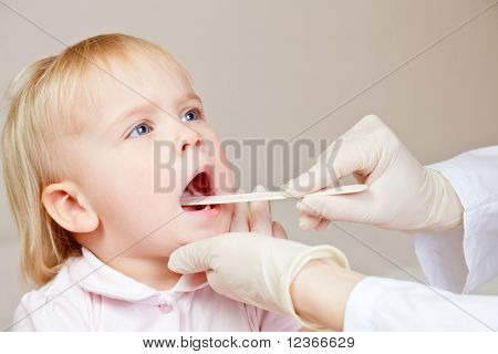 Küçük kızın boğazını dil depressor ile inceleyerek çocuk doktoru