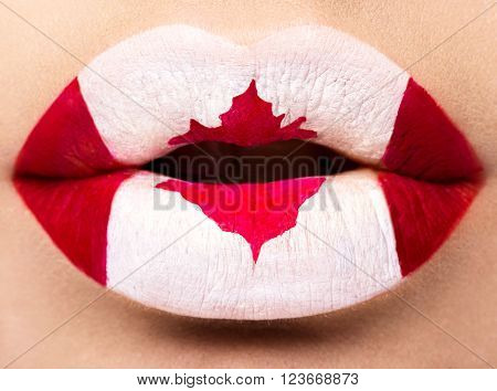 Female lips close up with a picture of the flag of Canada. Red, white, maple leaf