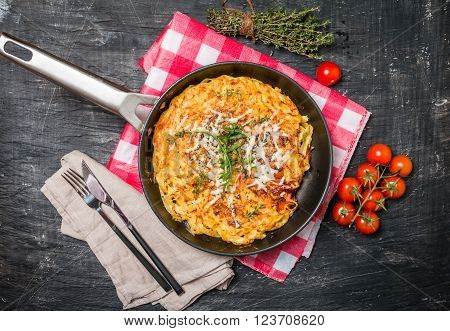 pasta casserole with eggs, sun-dried tomato and cheese in frying pan on black background, top view