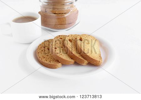 Healthy snack rusk, a type of bread, made from whole-wheat flour, in a plate and a cup of coffee and a bottle containing rusks.