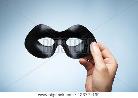 Man holding a black eyemask in his hand.