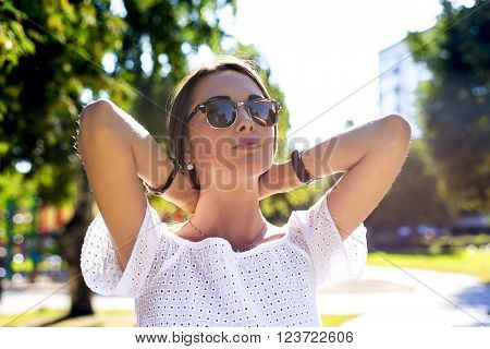 Summer, fashion and people concept - lifestyle portrait stylish pretty woman in sunglasses against colorful wall in city, street fashion among the trees, business brunette  girl resting