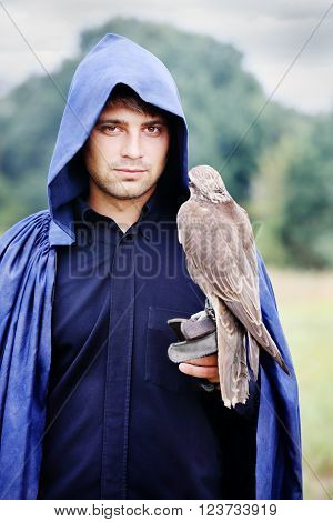 handsome young man in a raincoat with a falcon in his hand
