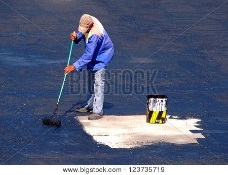 Man applying waterproofing glue on roof with a broom