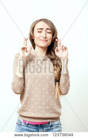 Beautiful girl making a wish. Woman in stylish clothes to makeup and hairstyle in studio isolated on white background. Bright positive emotions of young woman.