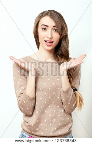 Woman in stylish clothes to make-up and hairstyle in studio on white background. Bright positive emotions of young woman. Beautiful girl showing surprise.