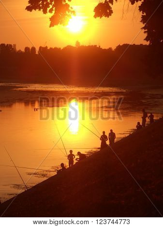 Fishermen and sunny summer evening on the river