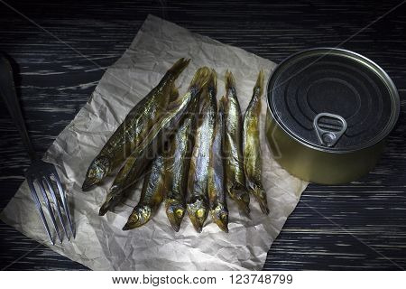 Smoked capelin and conserve tins on dark wooden background