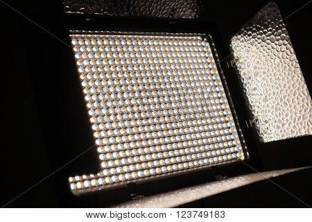 Professional LED Video and Photo light kit rack shot close up with a dark black background. The LED lighting is shining of the rig's barn doors.