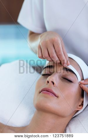 Woman getting her eyebrows shaped at spa