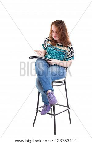 Beautiful smiling redhead plus size wreckled model with folder and ballpoint pen sitting on the bar chair. Isolated on a white background.