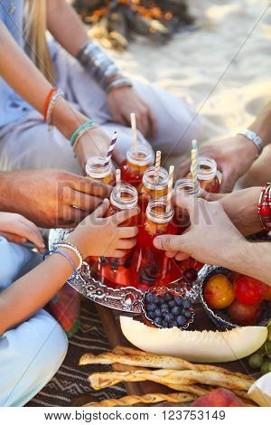 Group of friends holding drinks at the summer picnic. Close up
