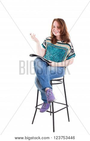 Beautiful smiling redhead plus size wreckled model with folder and ballpoint pen sitting on the bar chair. Isolated on a white background.