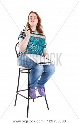 Beautiful smiling redhead plus size wreckled model with folder and ballpoint pen sitting on the bar chair. Isolated on a white background.