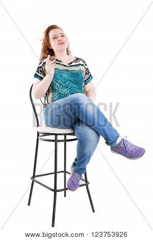 Smiling redhead plus size wreckled model sitting on the bar chair with cigar. Studio shot. Isolated on a white background.