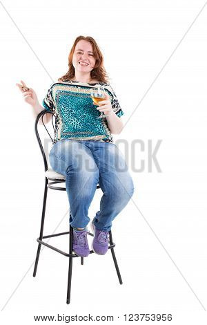 Smiling redhead plus size wreckled model sitting on the bar chair with glass of whiskey and cigar. Studio shot. Isolated on a white background.