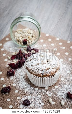 banana muffin with sunflower seeds and dried cranberries on a napkin with polka dots on wooden table selective focus
** Note: Shallow depth of field