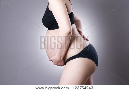Caucasian pregnant woman in black lingerie with back pain on gray studio background. Pregnancy concept