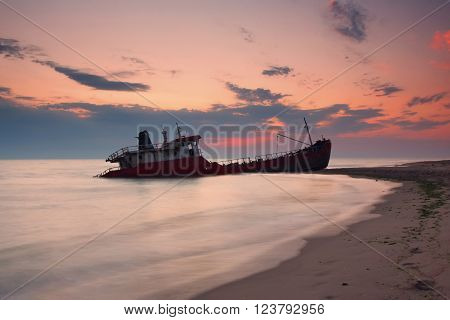 Ship after wreck on the coast colorful sunset
