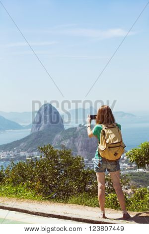 girl tourist taking a photo on a smartphone Pao de Acucar. Rio de Janeiro.