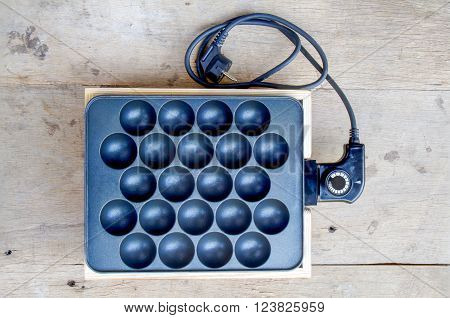 Takoyaki making electric machine on wood table. Top view.