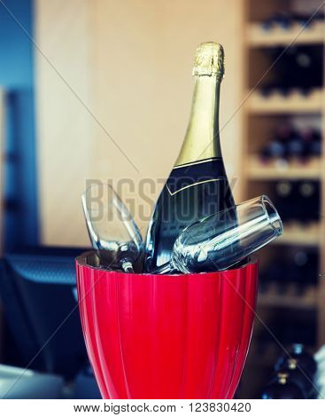 drink, holidays, celebration, alcohol and objects concept - close up of champagne bottle and glasses cooling in ice bucket at restaurant