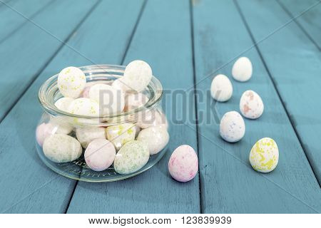 Easter eggs in glass pot on bright azure wooden planks toned selective focus
