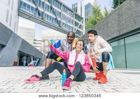 Multi-ethnic friends taking a selfie after a run in a urban area - Three runners resting after a workout session