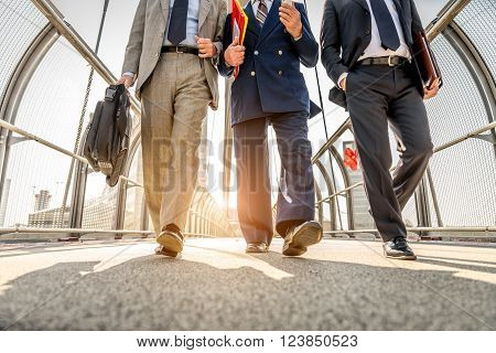 Three businessmen walking in a financial area while having a conversation - Work colleagues going to work