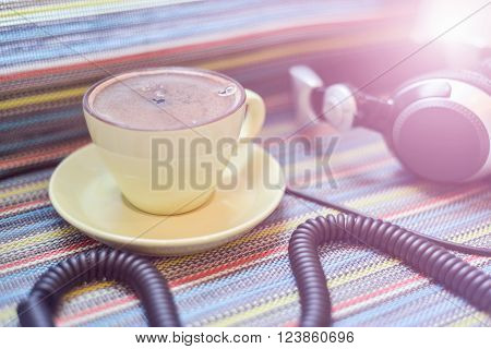 big headphones and cup with coffee on the colorful tablecloth
