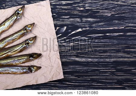 Smoked  capelin on dark vintage wooden background, top view