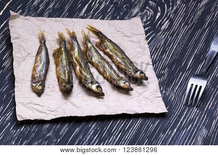 Smoked  capelin on dark vintage wooden background, top view