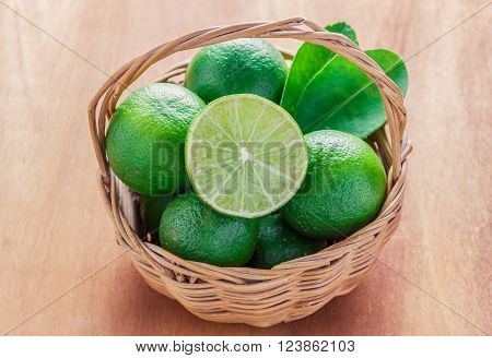 selective focus to slice fresh limegreen leaf lime on also many lime in the wood basket.Wood basket on the wood background.