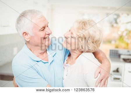 Happy senior couple smiling while looking at eachother at home