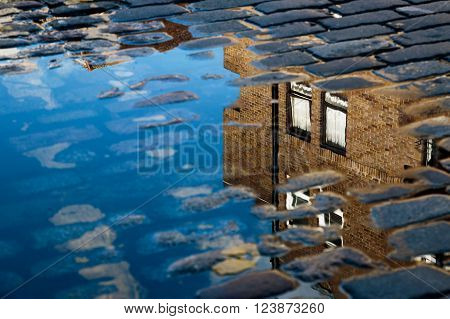 Cobblestone with reflection of house in puddle after rain