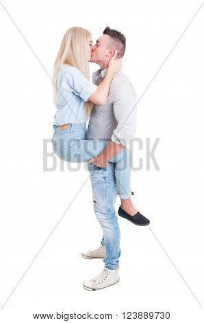 Man holding woman by legs with his strong arms. Full body couple kissing on white background