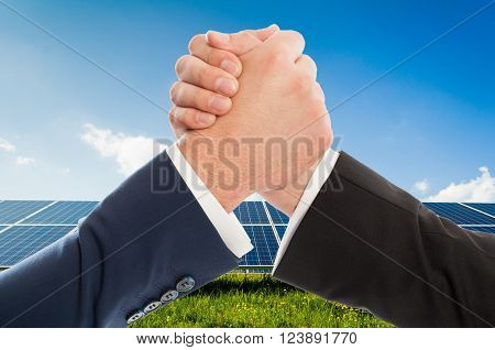 Businessmen handshake as teamwork on solarpower photovoltaic panel background. Renewable energy partnership agreement