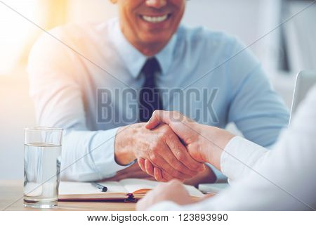 Good deal. Close-up of two business people shaking hands while sitting at the working place