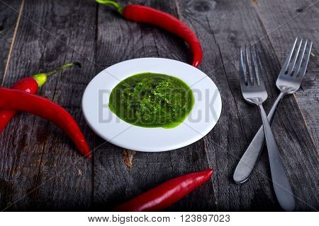 Green and hot herb sauce chimichuri from chili, oregano, parsley, oil on wood background