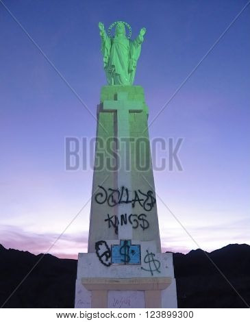TUPIZA, BOLIVIA - SEPTEMBER 21, 2007:  Statue of Jesus Christ with graffiti of Dollars signs showing the dichotomy of spiritualism and materialism.