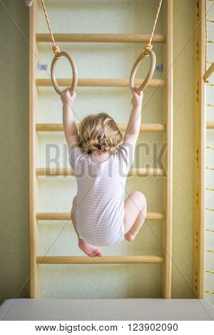 Baby kid playing sports on the gymnastic rings in the gym class. Back view.
** Note: Soft Focus at 100%, best at smaller sizes