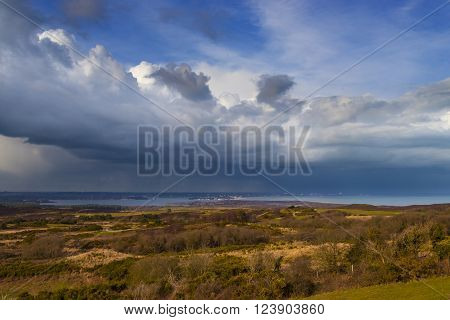 Rain-bearing clouds hang over the horizon casting reflections in the still waters off the Dorset coastline