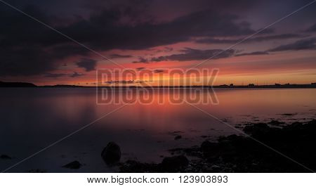 Tranquil waters and orange sun glow over still seas