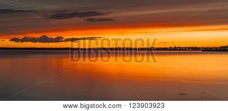 Tranquil waters and orange sun glow over still seas