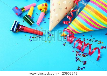 Birthday hats with serpentine streamer and noise makers on blue background