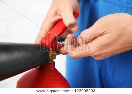 Male hands pulling safety pin of fire extinguisher closeup